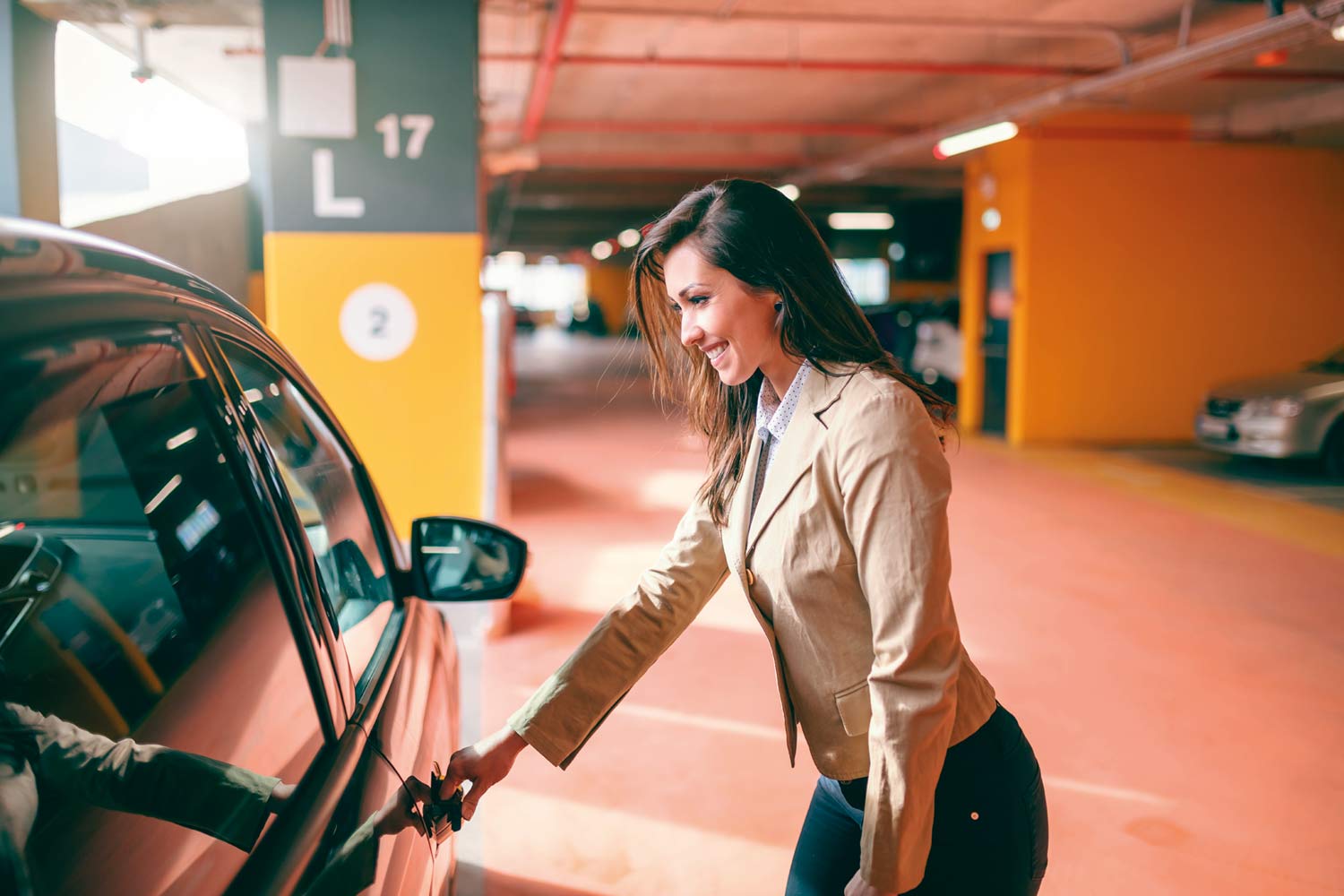 Mulher a entrar em carro estacionado em parque de estacionamento coberto