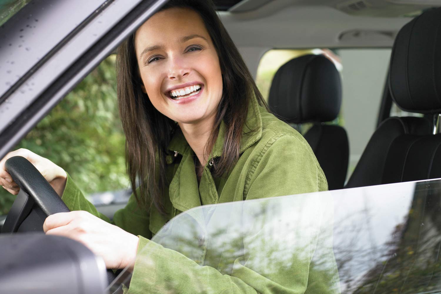  Mulher em automóvel, no lugar do condutor, a olhar para a janela com um sorriso 