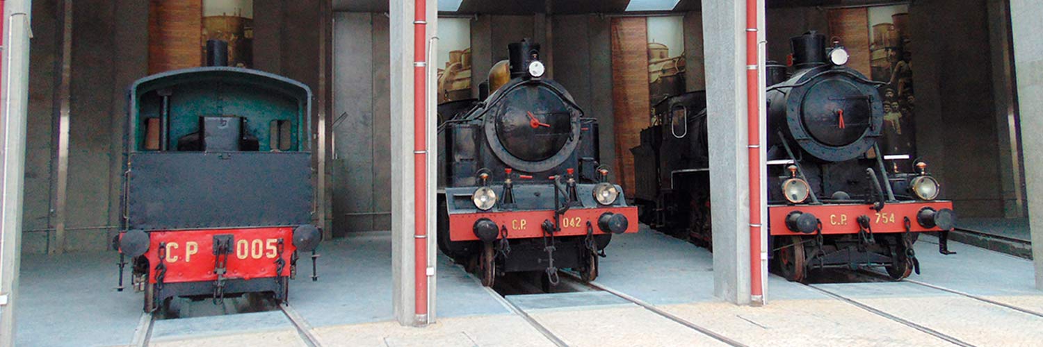 Vista frontal de 3 locomotivas históricas no Museu Nacional Ferroviário.