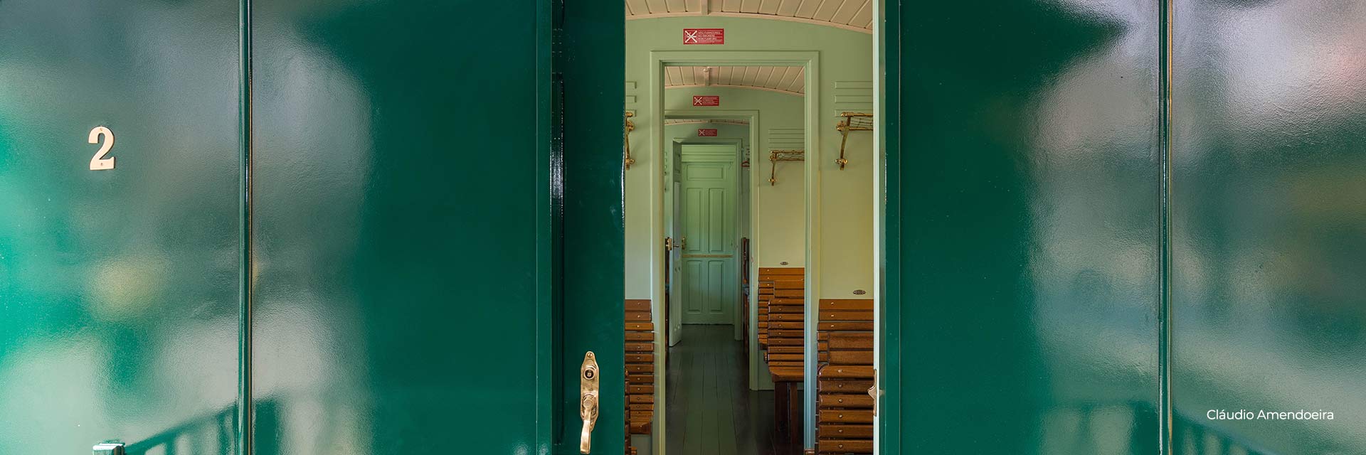 Interior of a historic carriage, from the corridor to the spaces with wooden benches and a door at the back.