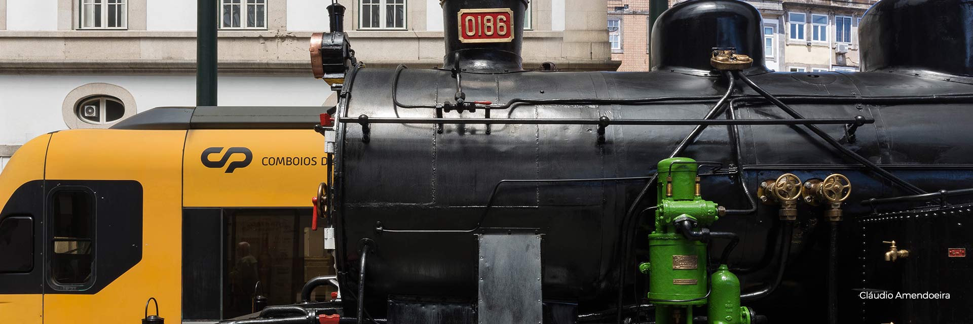 Parked side by side in the foreground are the CP 0186 steam locomotive and a Porto urban train.