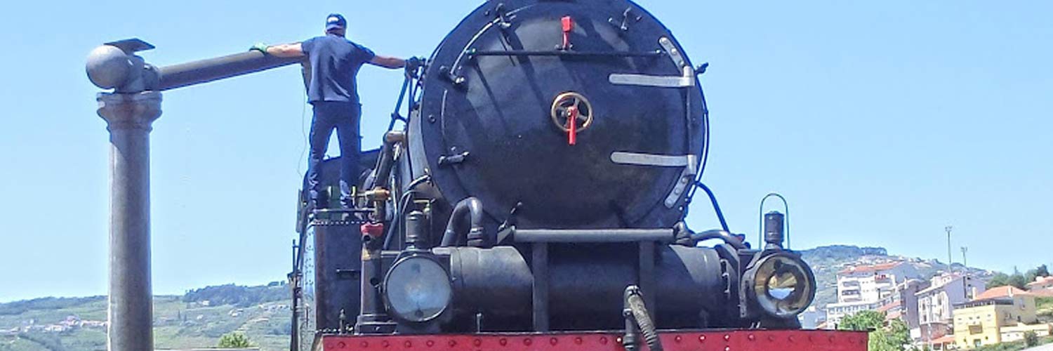 A close-up of the top of the steam locomotive, showing a  crew member refilling the water tank.