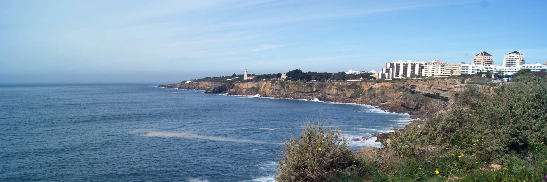 View of cliffs overlooking the sea, buildings of Guia and the Guia lighthouse.