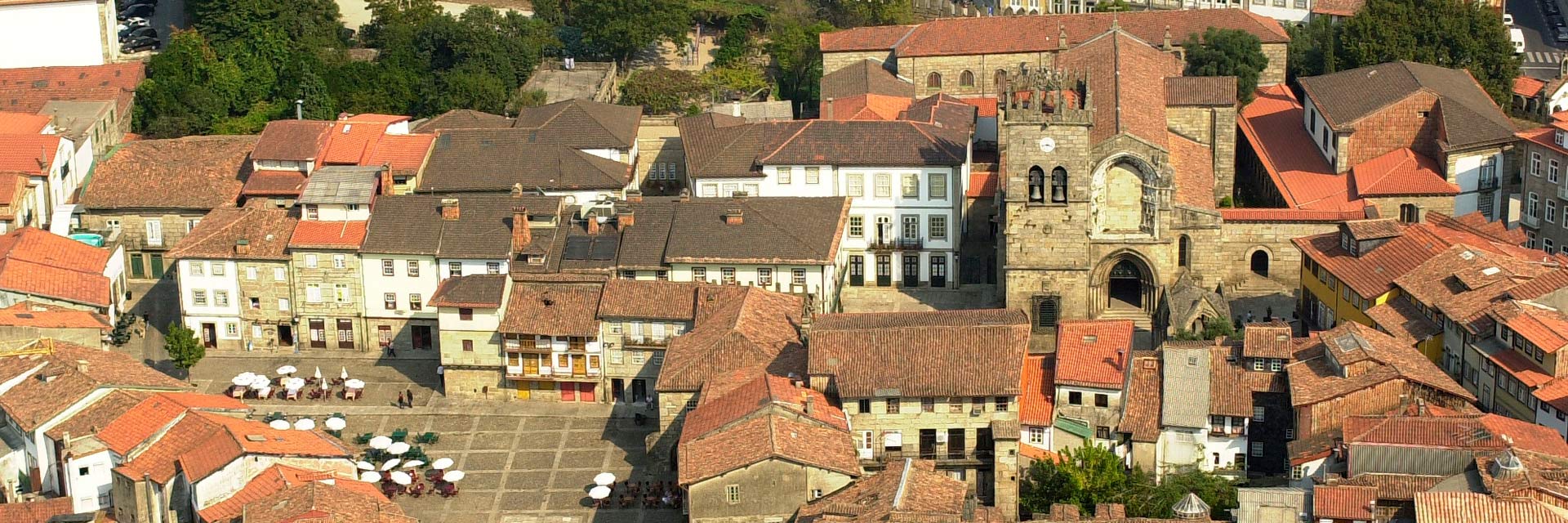 Aerial view of the historic center, with rooftops, a square, and a stone church.