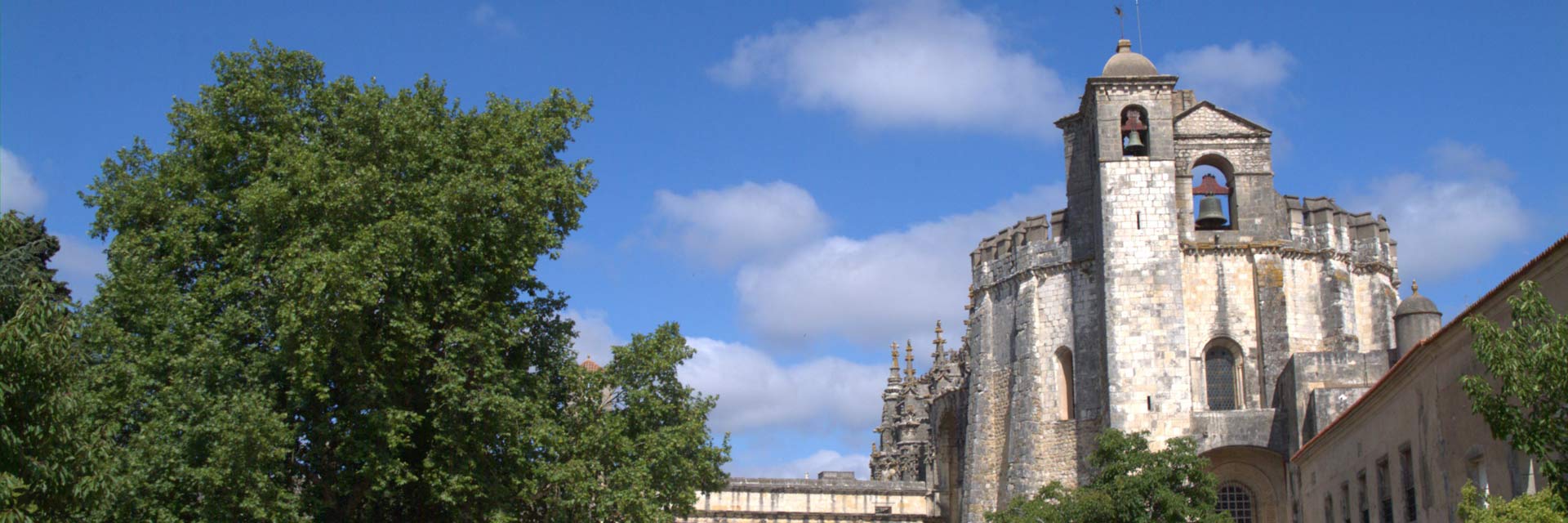 Church of the Convent of Christ with two bell towers and a leafy tree.
