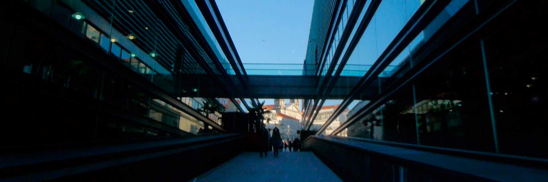 Arquitetura moderna de um edifício em Vigo em contraste com uma igreja antiga no fundo.