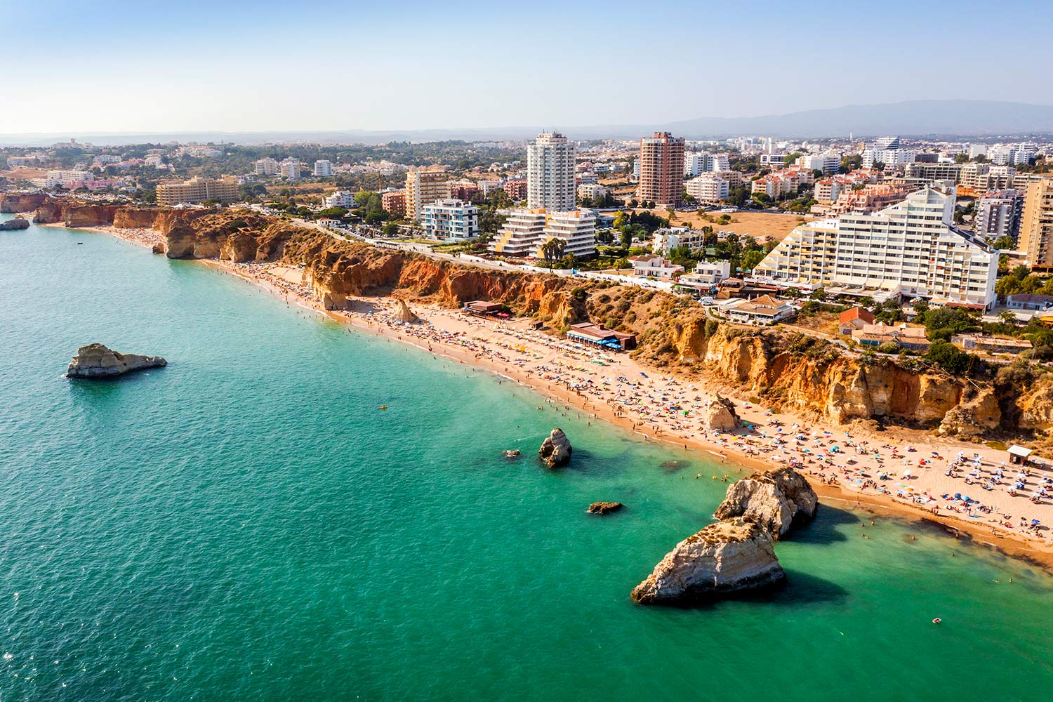 Vista aérea sobre Portimão, com praia e prédios junto à costa marítima.