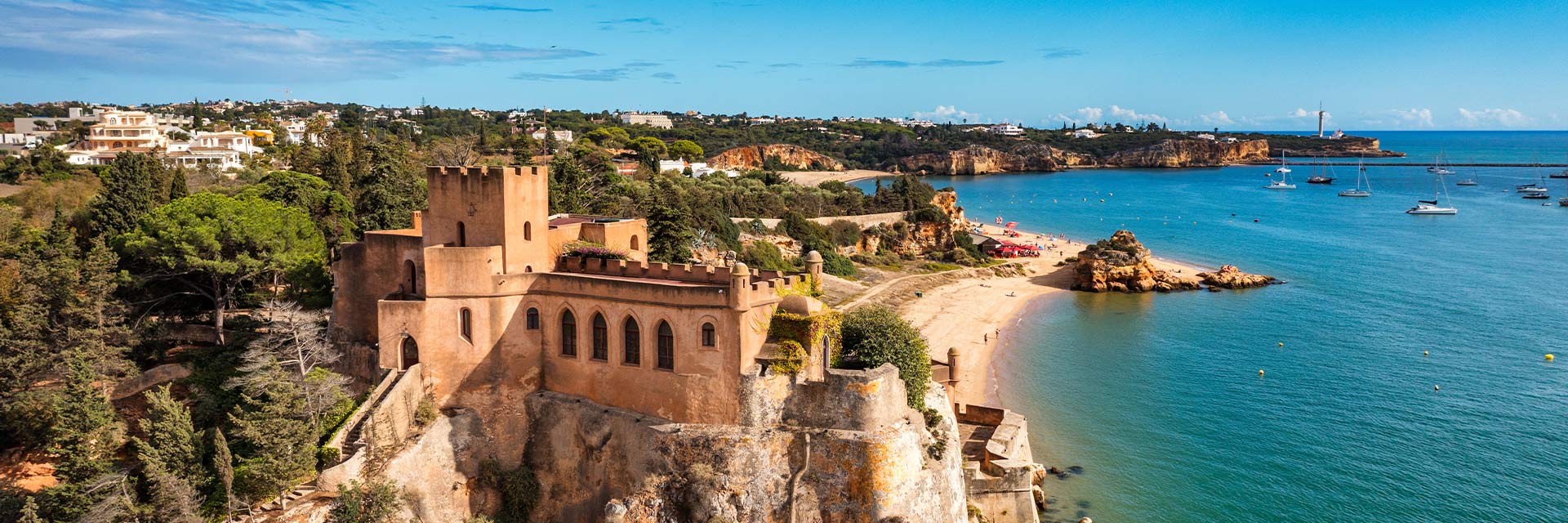 Vista aérea sobre a vila de Ferragudo, o Forte e a orla costeira.