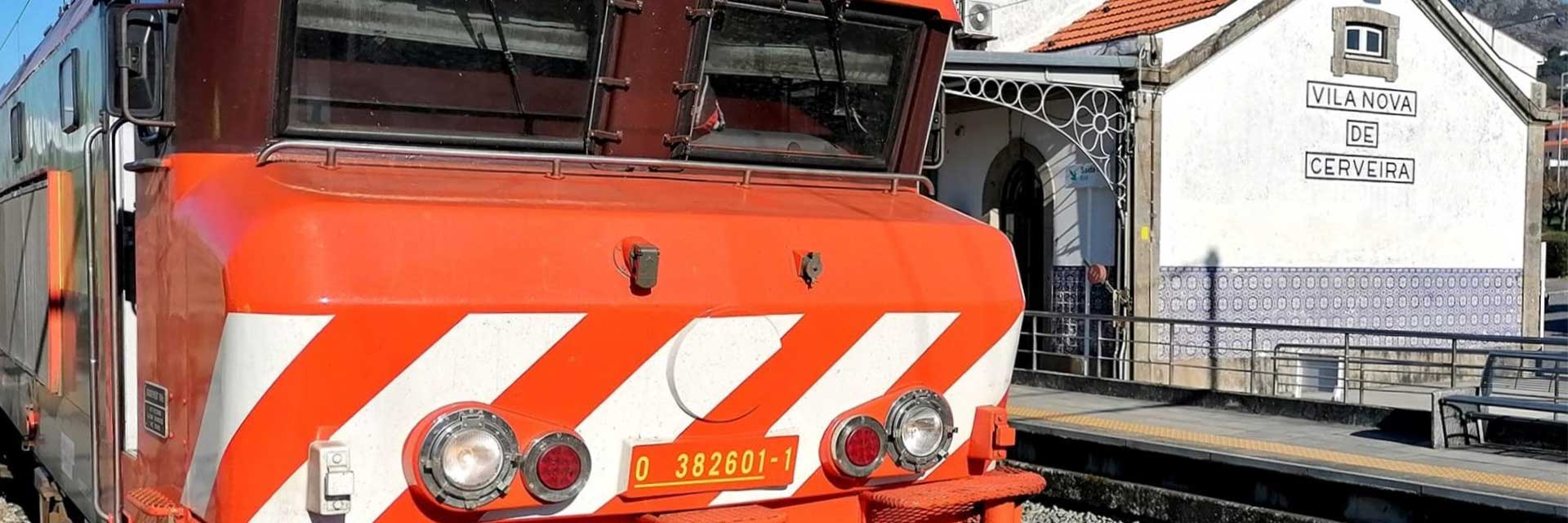 Comboio Inter-regional, com locomotiva elétrica CP 2600 em tons de laranja e castanho, na estação de Vila Nova de Cerveira.