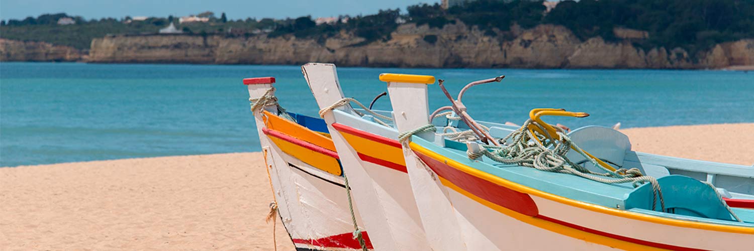 a close-up of three white boats with yellow and red stripes, on the beach by the sea