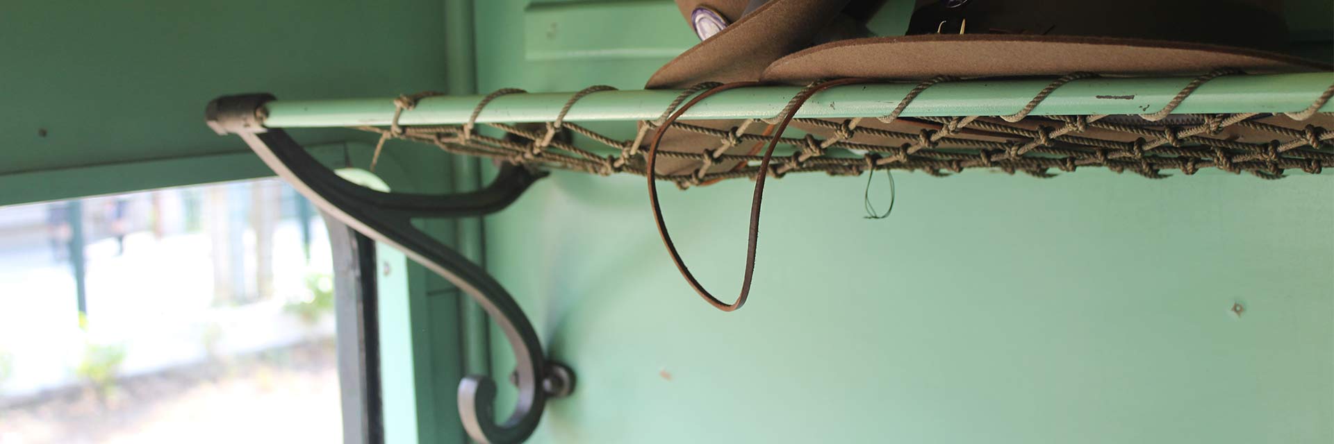 Interior of a historic carriage: detail of the metal and rope support, located above the seats, for small luggage.