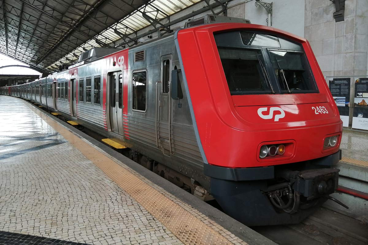 CP 2400 series electric unit with red and gray livery, stopped on one of the station platforms.