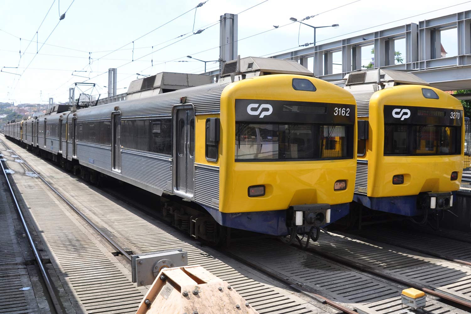 Imagem a cores das automotoras elétricas da série CP 3150 e 3250, cores cinza e amarelo, na estação do Cais do Sodré.