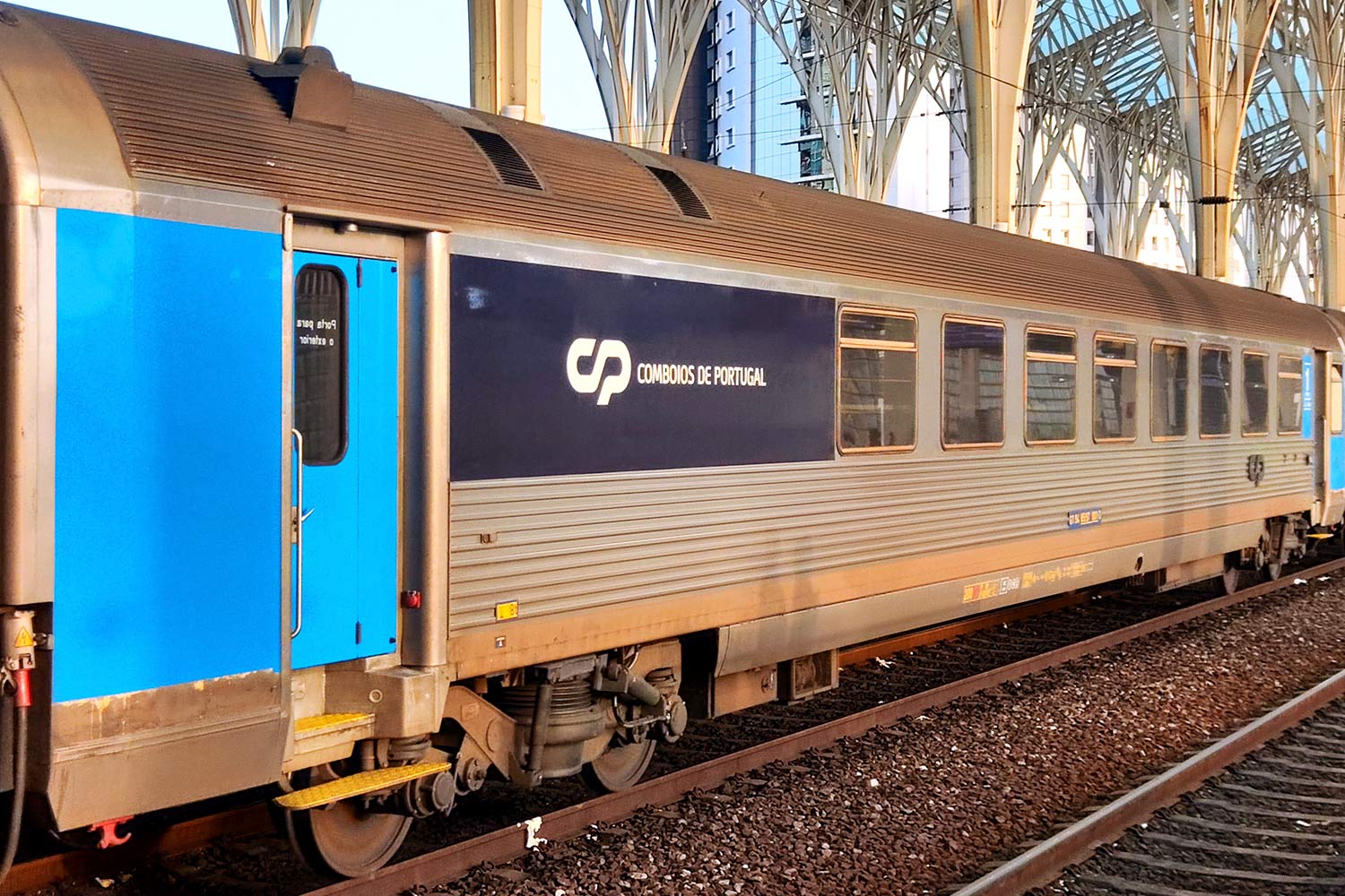 Carruagem Corail de 1ª classe com bar cor azul e cinzento, parada numa das linhas da estação.
