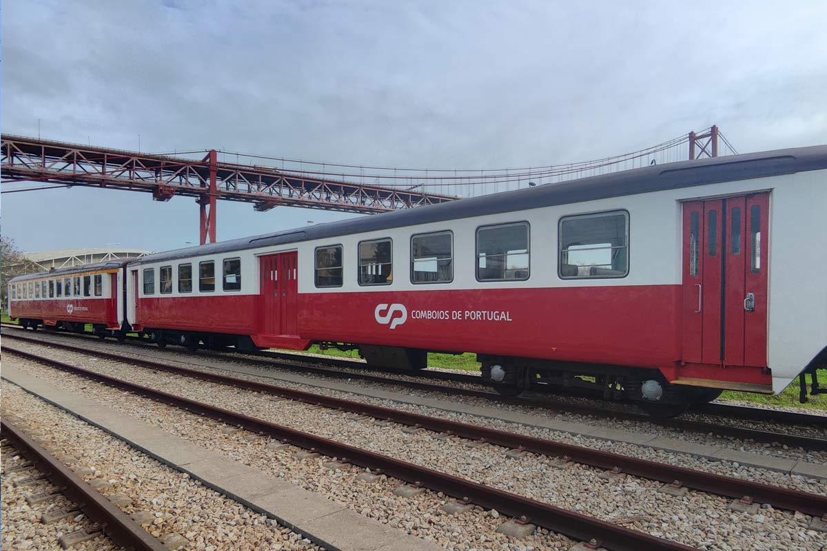 Schindler 1st and 2nd class white and red coaches stopped on one of the platforms next to the River Tagus.