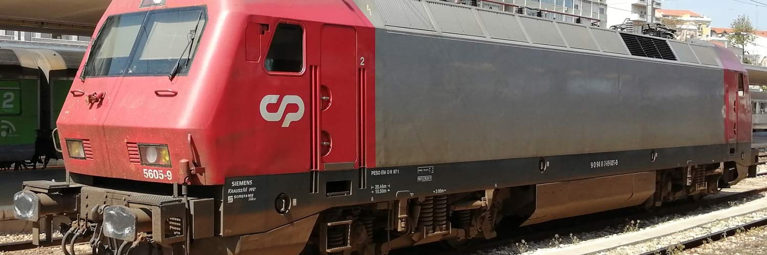 CP 5600 series electric locomotive with gray and red livery stopped in one of the station lines.