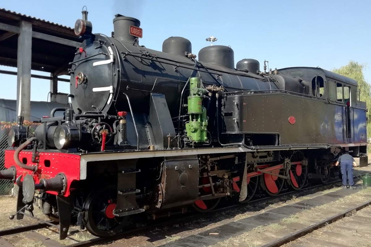 Locomotiva a vapor CP 0186, cor preto e vermelho parqueada numa das linhas da estação.