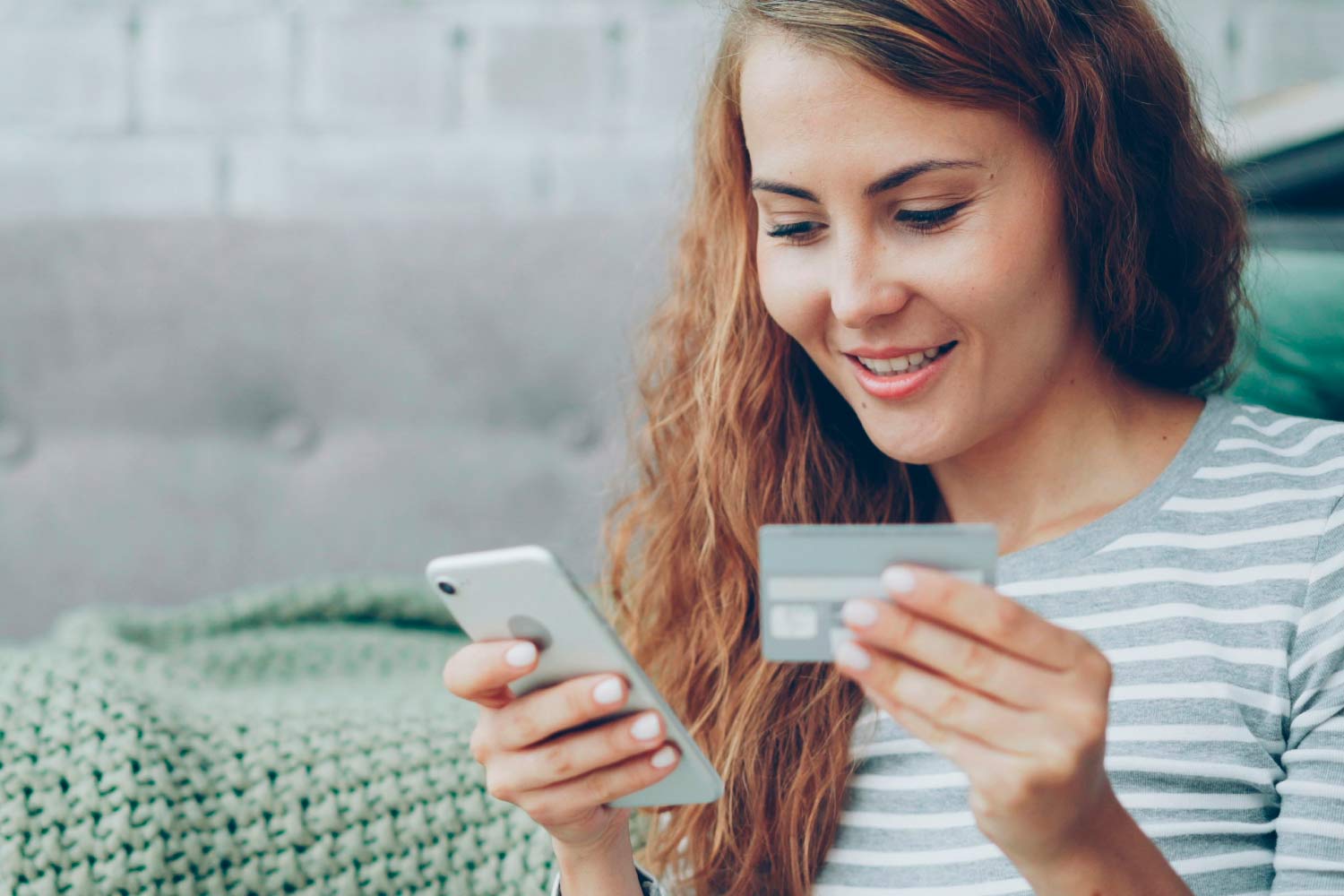 mulher com um telemóvel na mão direita e um cartão na esquerda