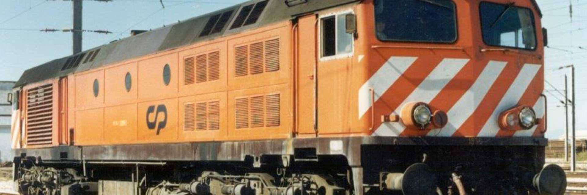 A CP 1960 diesel locomotive painted orange, brown and white, standing in a station.