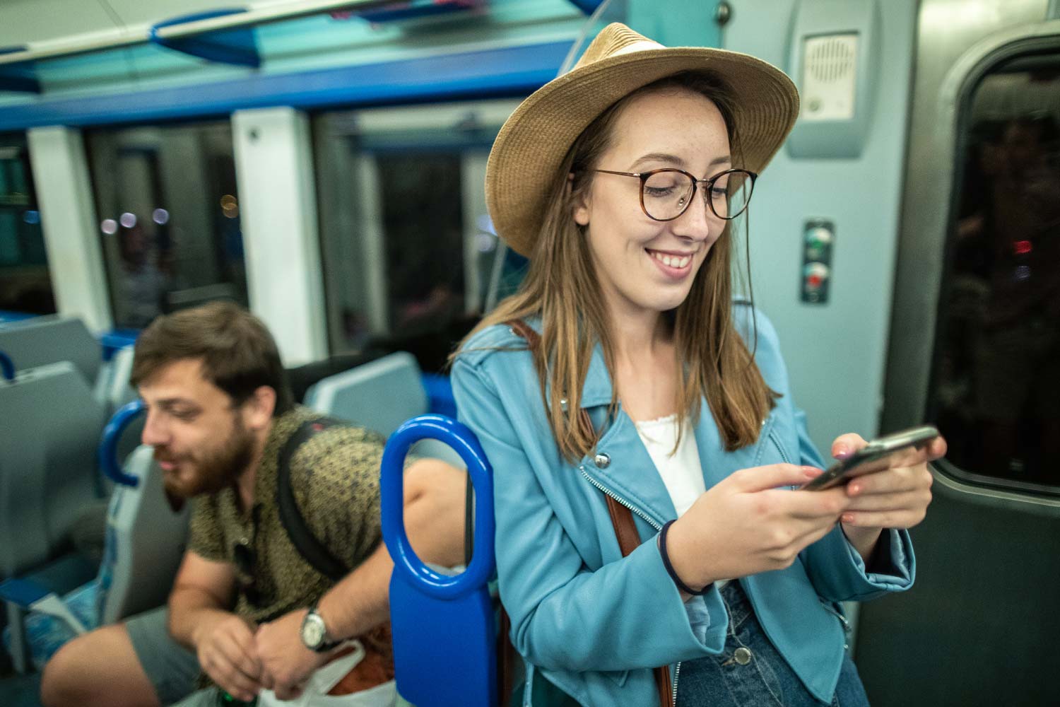 Cliente ao telemóvel junto à porta, no interior de carruagem de um Comboio da Linha de Cascais.