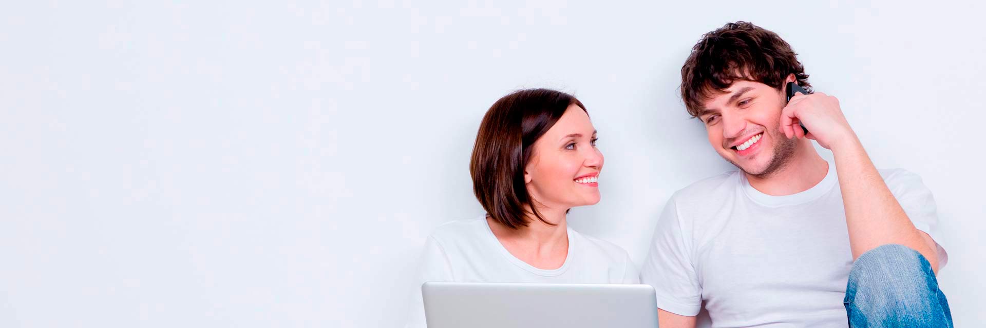 Rapaz sentado no chão ao telemóvel junto de rapariga ao portátil.