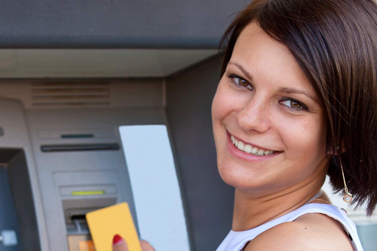 Young woman inserting a card into an ATM machine.