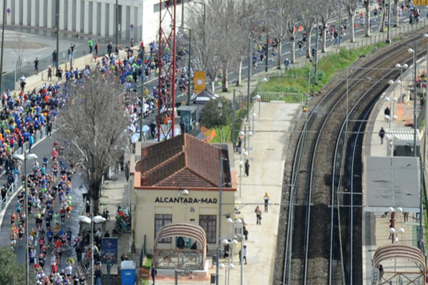 Pessoas a correr na rua junto à estação de Alcântara-Mar, Linha de Cascais.
