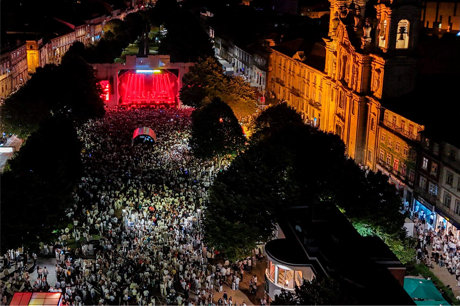 Imagem aérea noturna de pessoas junto a palco no centro de Braga.