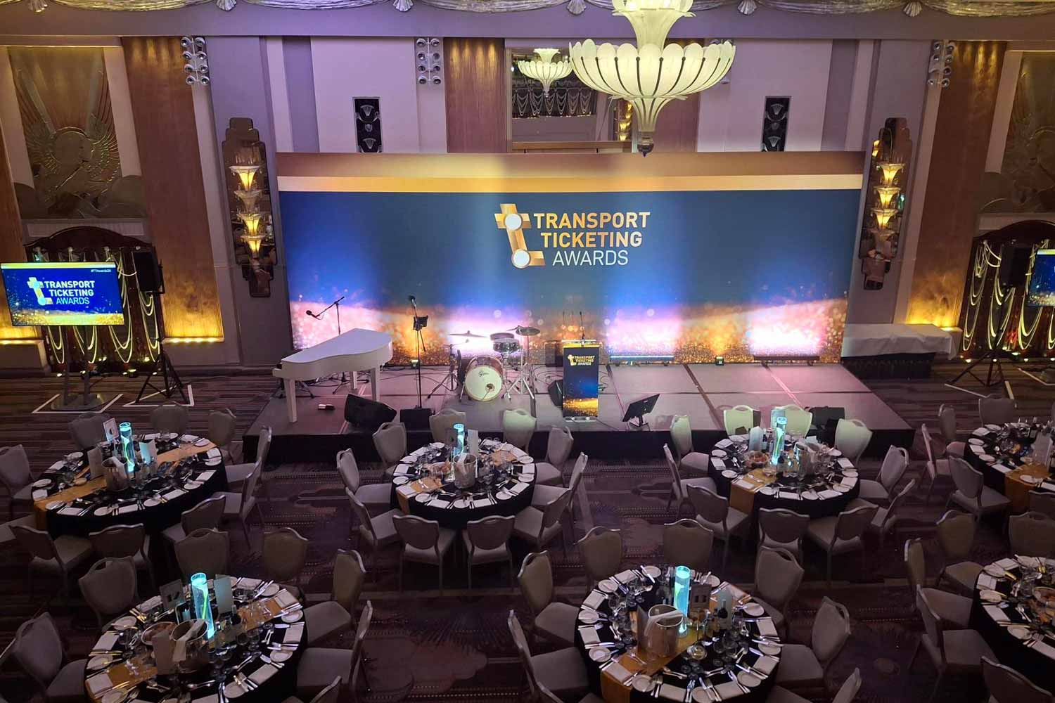 Sala com mesas e cadeiras e palco onde decorreu o jantar com a entrega de prémios.